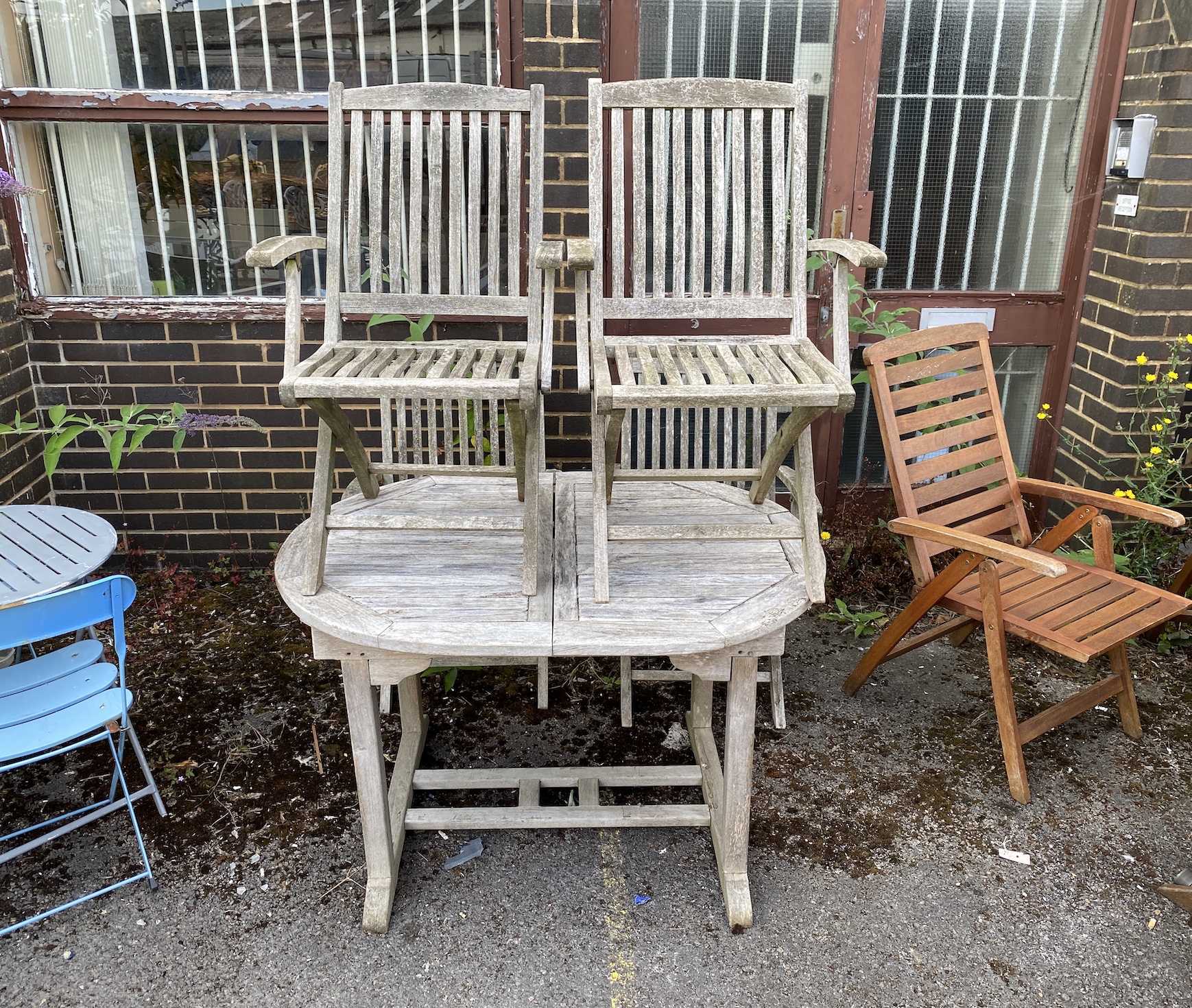 A weathered teak garden table, length 121cm, depth 89cm, height 75cm, and four folding elbow chairs
